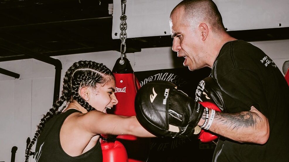 Coach holding focus mitts as a boxer throws a punch at Boxing N' More